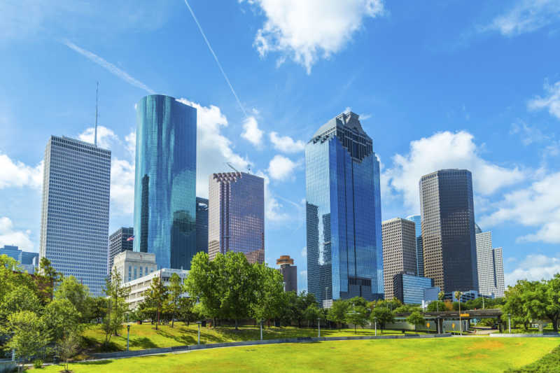 Five skyscrapers with a blue sky and clouds in Houston.