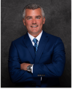 John Lancione standing with his arms crossed in a dark blue suit