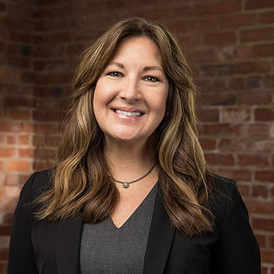 Bridget N. Long smiling in a room with a brick wall