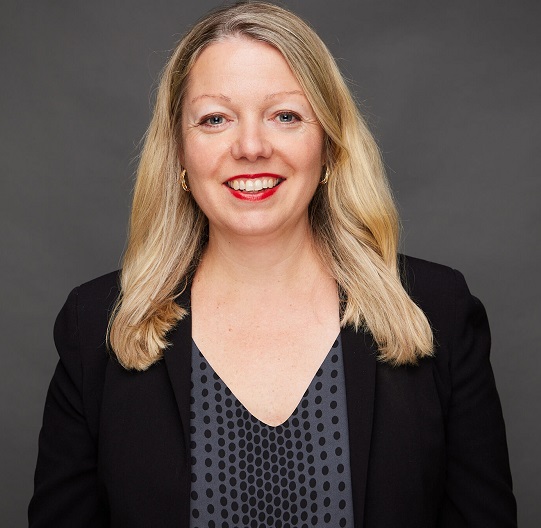 Anne Doohan wearing a dark blazer in front of a grey background.