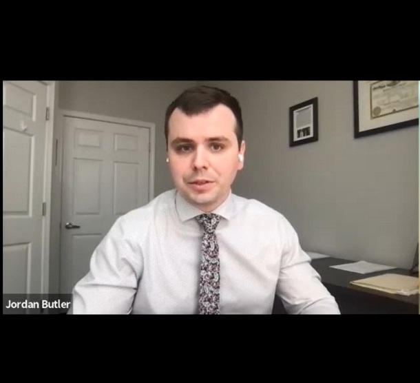 Jordan Butler wearing white shirt and tie in front of white door.