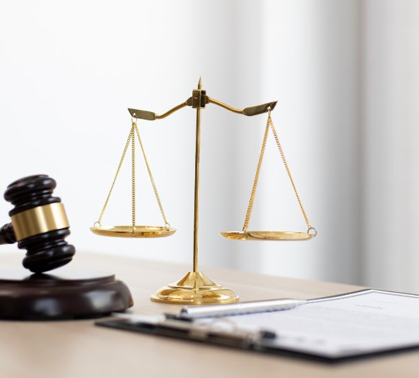 A photo of the scale of justice on a table with a gavel in the bakground